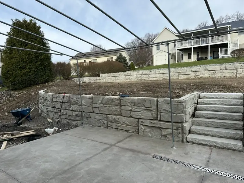 Two tier Magnum Stone retaining wall with built-in steps beside a new concrete slab