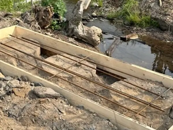 Wooden forms with rebar set beside the stream for the new abutments