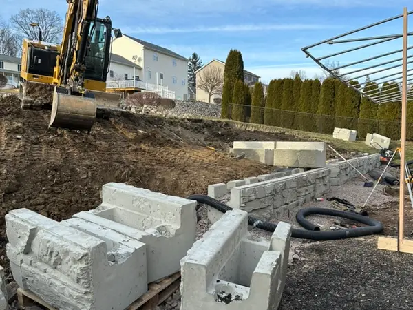 Excavator staging Magnum Stone blocks beside the lower wall