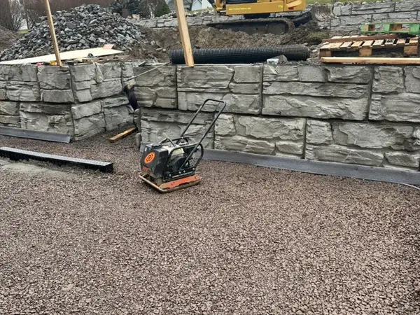 Both wall tiers in place with a compactor and excavator on site