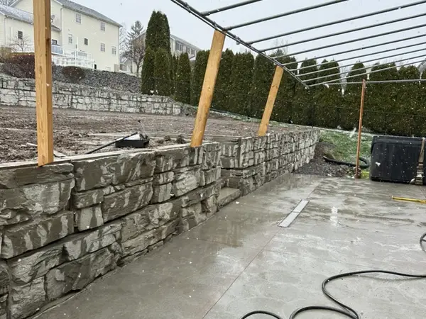 Fresh concrete slab against the lower wall under a pergola frame